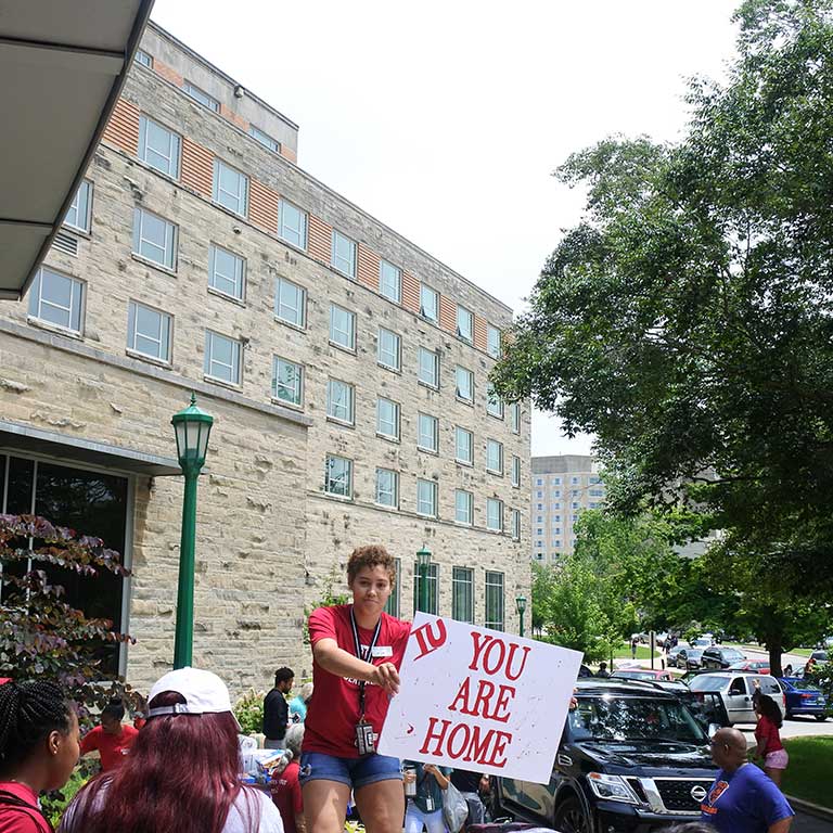 Student holds up say that says IU you are home during move in week.